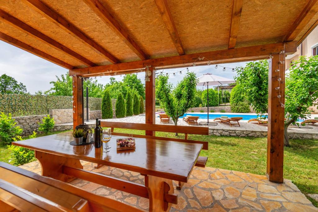 a wooden pergola with a wooden table on a patio at Villa Prima Natura, Imotski private pool in Imotski