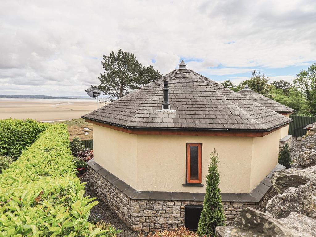 a small building with a roof on top of a hill at Oversands Cottage in Grange Over Sands