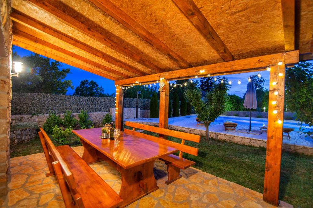 a wooden pergola with a wooden table and benches at Villa Prima Natura, Imotski private pool in Imotski