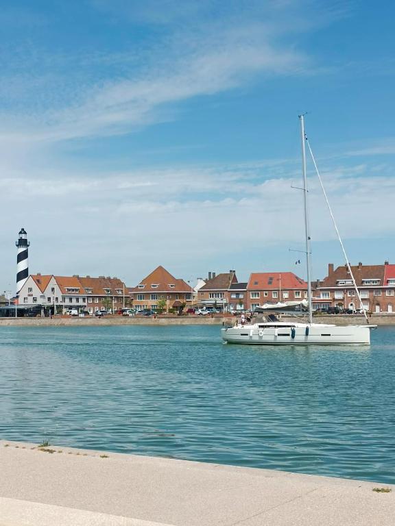 un bateau assis dans l'eau devant les maisons dans l'établissement Studio Mer & Aa-terrasse-jardin-WIFI-parking-classé 3 étoiles, à Grand-Fort-Philippe