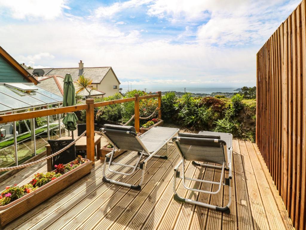 a deck with two chairs and a table on it at Sunswept in St Austell