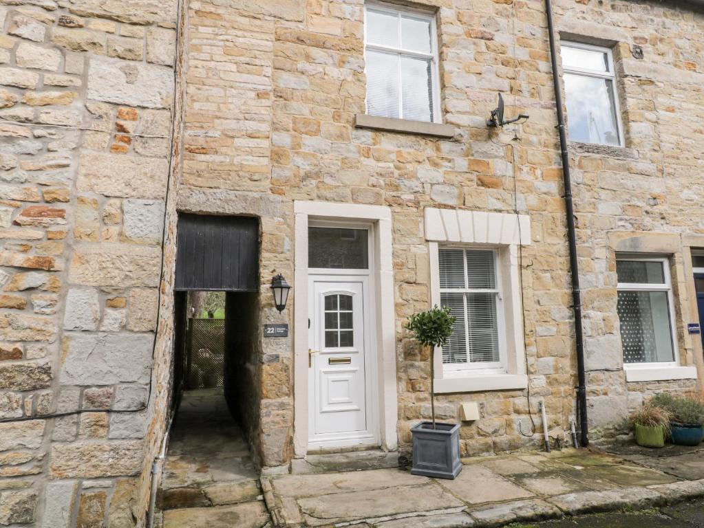 a stone building with a white door and windows at Ermysted's Cottage in Skipton