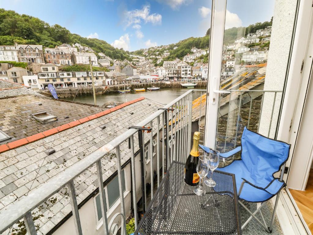 a balcony with a bottle of wine and a chair at Harbour Hideaway in Looe