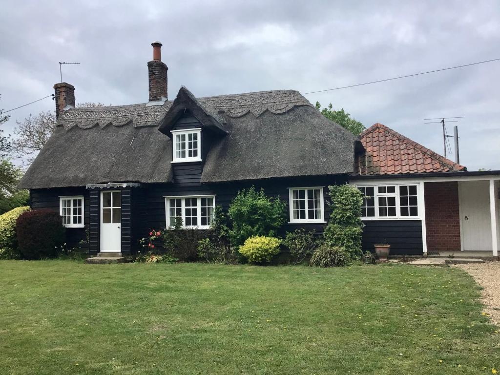 a black house with a thatched roof at Thatched Cottage Wix in Wix
