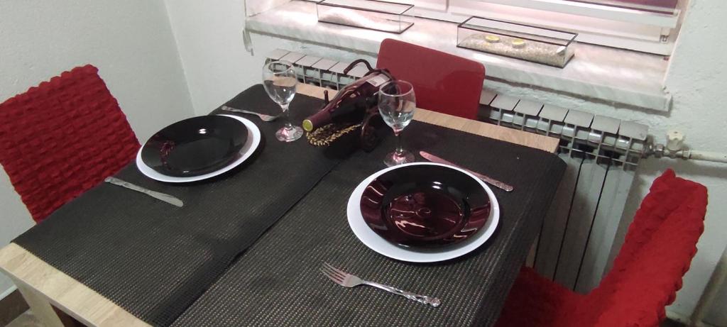 a table with two plates and wine glasses on it at Lara in Doboj