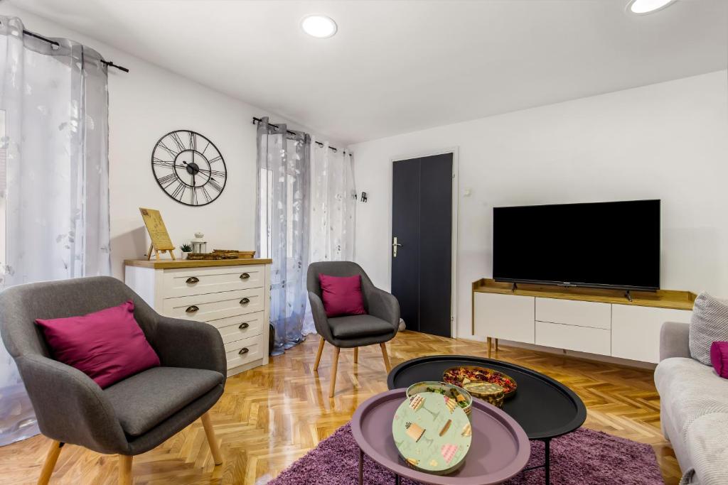 a living room with a tv and two chairs and a table at Apartment Sancti Viti in Rijeka