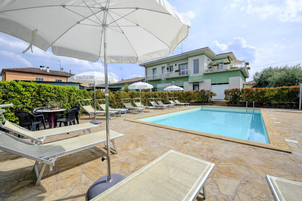 a swimming pool with chairs and an umbrella at La Forgia Apartments in Peschiera del Garda