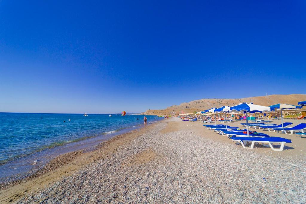una spiaggia con sedie e ombrelloni e l'oceano di Amaryllis front beach hotel a Lárdos
