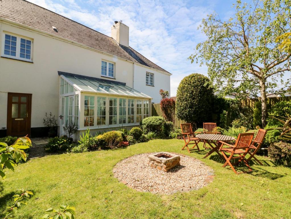 a garden with a table and chairs in front of a house at Home Farm Cottage in Barnstaple