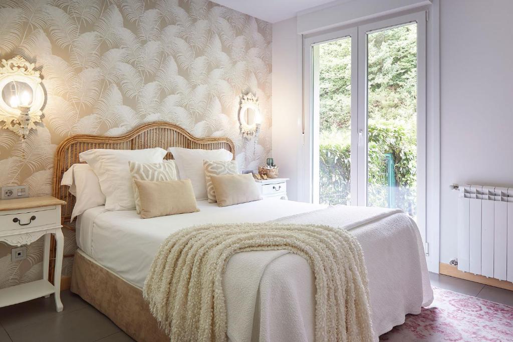 een slaapkamer met een wit bed en een groot raam bij Hotel Boutique Txanka Erreka PARKING INCLUIDO in Orio