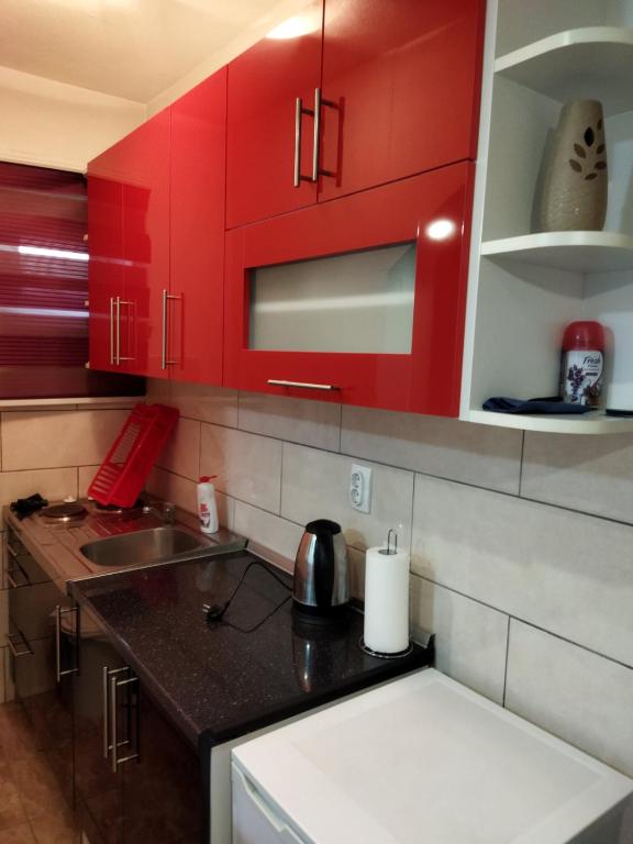 a kitchen with red cabinets and a black counter top at Lara in Doboj