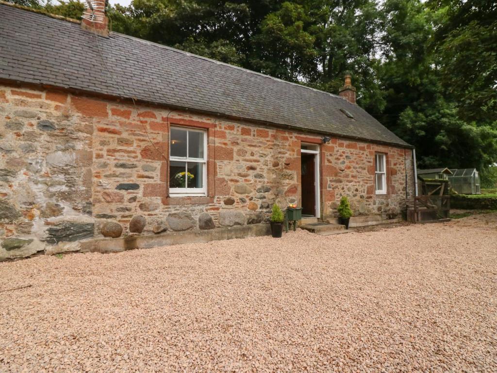 an old brick building with a window and a door at Gardener's Cottage in Forfar