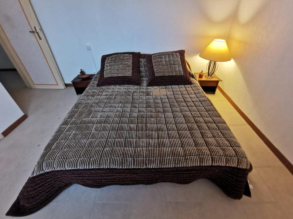 uma cama grande num quarto com um candeeiro em PROVENCE, SOLEIL ET LUBERON !!! Coin jardin 3 Lits 2 Chambres 80 m2 em Cheval-Blanc