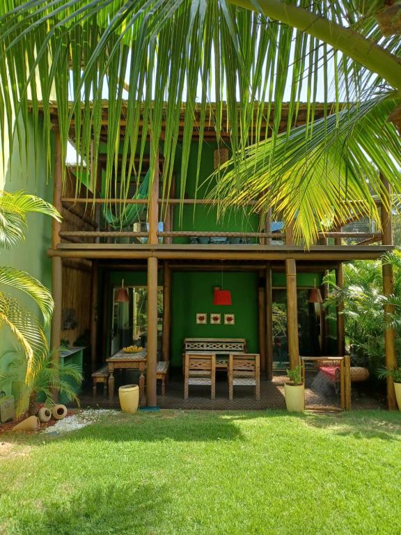 a house with a table and a green wall at Bangalô duplex à beira-mar in Camaçari