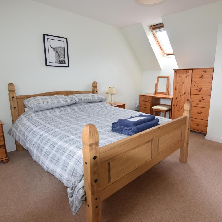 1 dormitorio con cama de madera y manta azul en Moray Cottages, en Dufftown