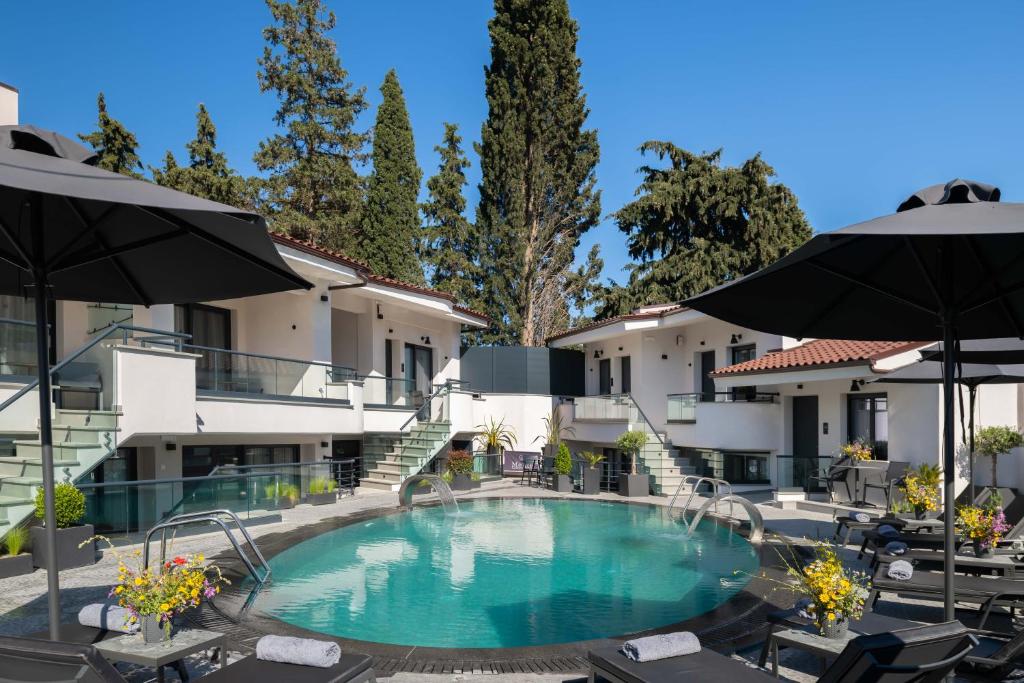 a pool at a hotel with chairs and umbrellas at Melite Luxury Rooms & Apartments in Paliouri