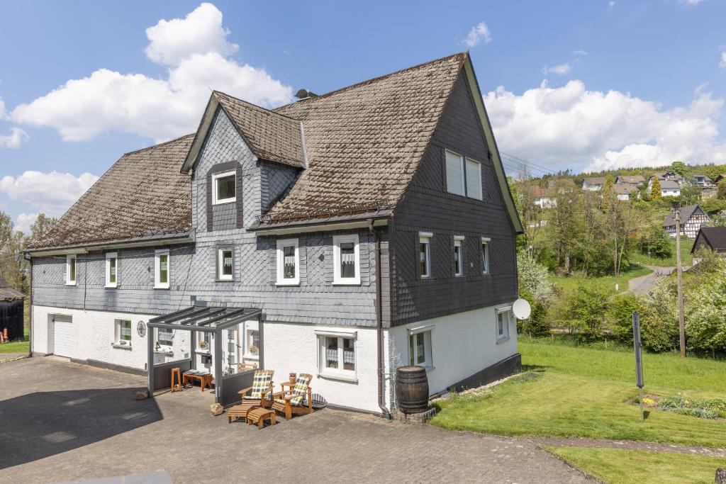 uma grande casa branca com um telhado preto em Ferienhaus Broche em Hilchenbach