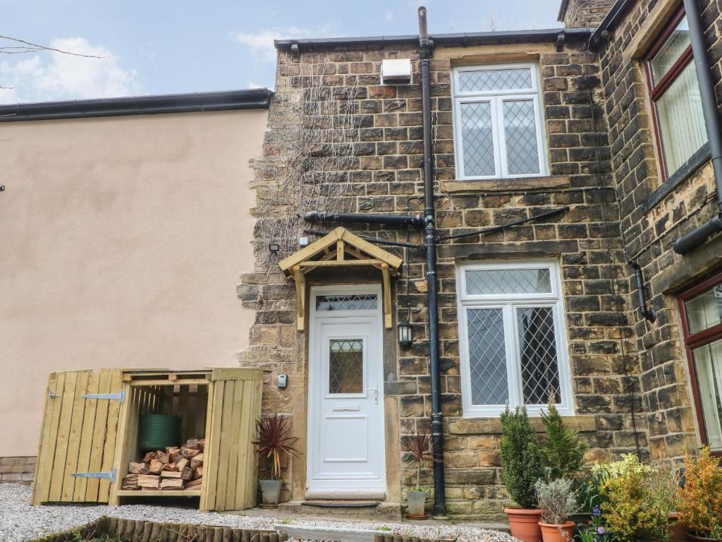 a stone house with a white door and a wooden box at 10 West Cottages in Oldham