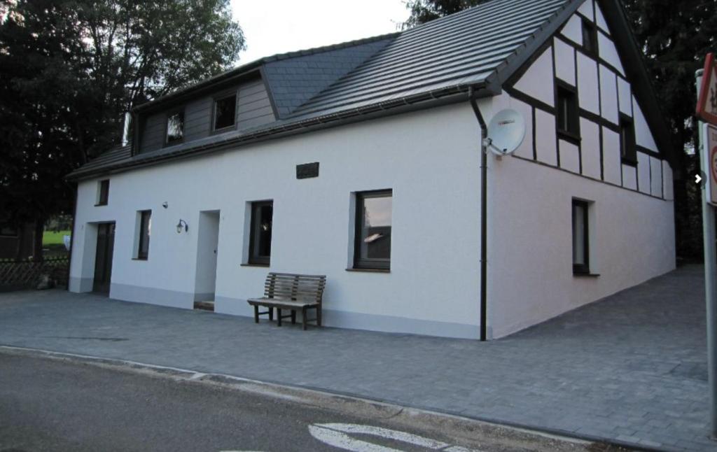 um edifício branco com um banco à frente em Zur alten schule em Amblève