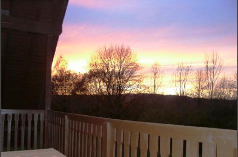 a sunset on a porch with a white fence at Apartments Mester in Xanten