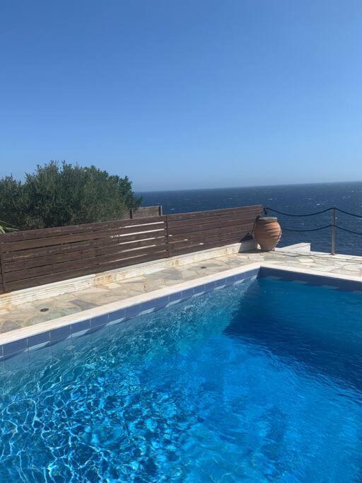 a swimming pool with a bench and blue water at Κυκλαδίτικη μεζονέτα με πισίνα και απεριόριστη θέα in Sinétion