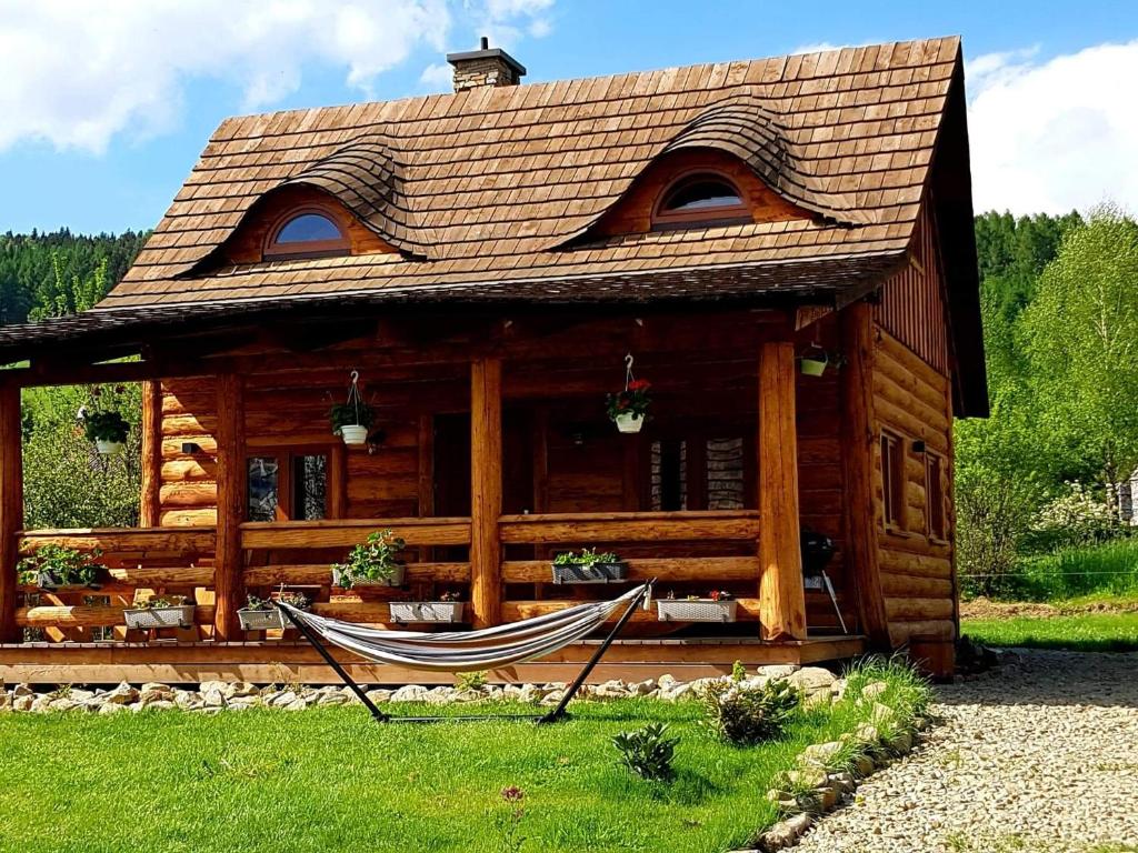 a log cabin with a hammock in front of it at Tylickie Chałupy in Tylicz