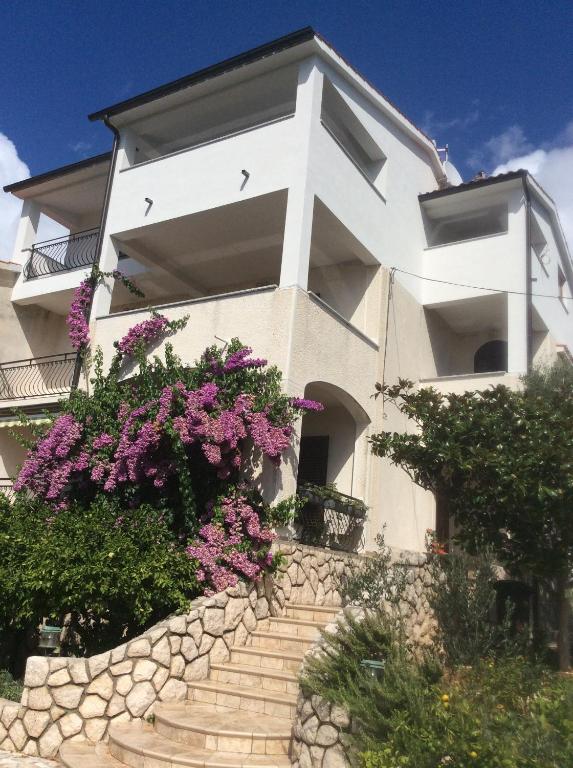 a white house with flowers on the stairs at Villa Jadranka Rab apartman Nick in Rab
