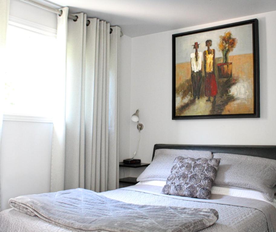 1 dormitorio con 1 cama y una foto en la pared en Le Marigot, en Vaudreuil-Dorion
