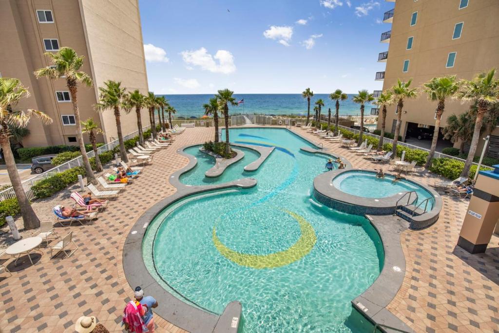 a pool at a resort with palm trees and the ocean at Crystal Tower 1906 by Vacation Homes Collection in Gulf Shores