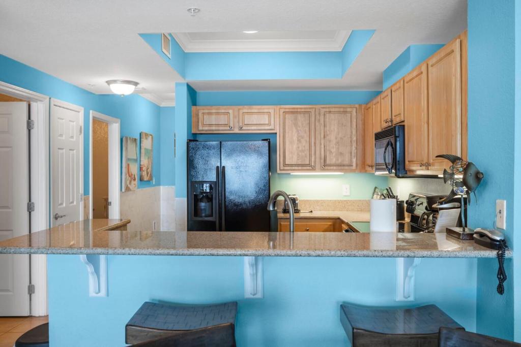 a kitchen with blue walls and a black refrigerator at Crystal Tower 1906 by Vacation Homes Collection in Gulf Shores