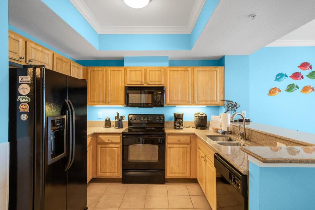 a kitchen with wooden cabinets and a black refrigerator at Crystal Tower 1906 by Vacation Homes Collection in Gulf Shores