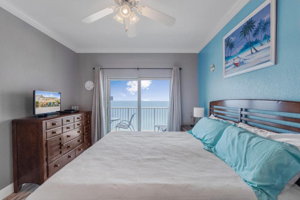 a bedroom with a bed and a television and a balcony at Crystal Tower 1906 by Vacation Homes Collection in Gulf Shores