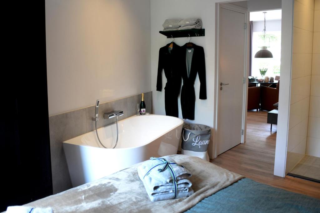 een slaapkamer met een bad en een pak aan de muur bij Bed and Breakfast in de buurt in Waalwijk