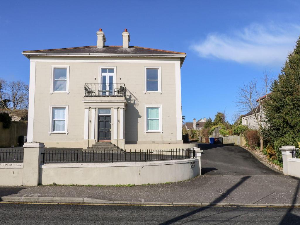 Une grande maison blanche avec balcon est située dans une rue. dans l'établissement Beachcomber, à Ballycastle
