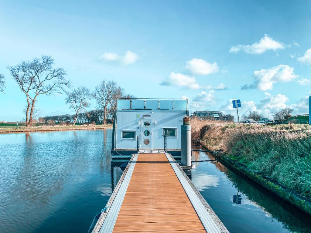 a boat is docked at a dock on a river at Homeboat Glamping in Nieuwpoort