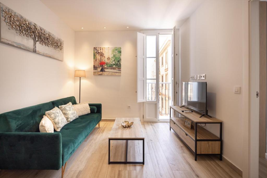 a living room with a green couch and a tv at El Rincón de Fabio Little Apartments in Cádiz