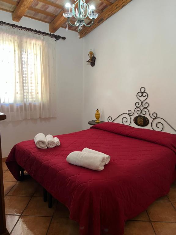 una camera da letto con un letto rosso e asciugamani di Baglio Cracchiolo da Tuzzo - Casa Carrubbo a San Vito lo Capo