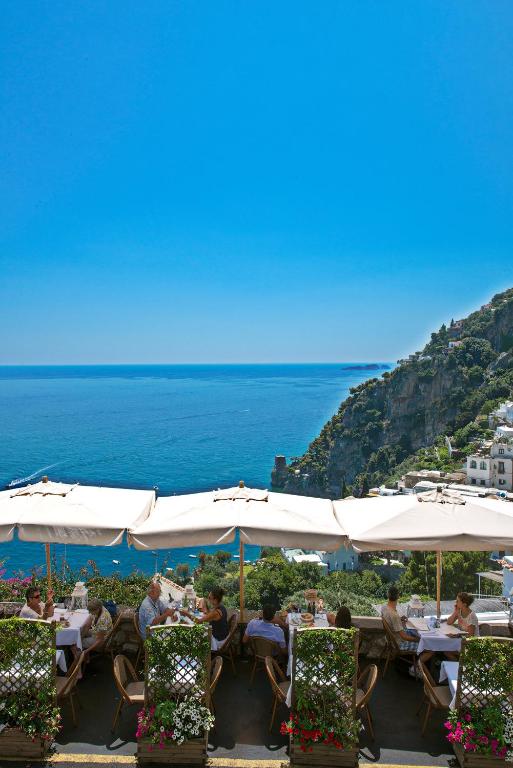 a group of people sitting at tables under white umbrellas at Hotel Villa Gabrisa in Positano