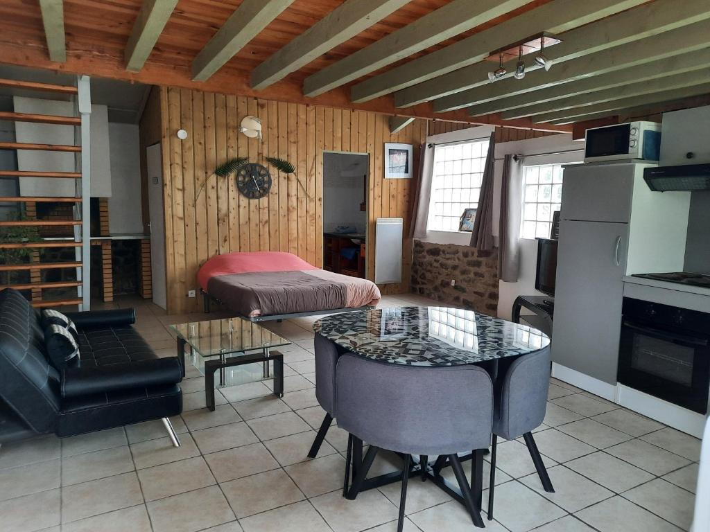 ein Wohnzimmer mit einem Tisch und ein Zimmer mit einem Bett in der Unterkunft Gîte de la Nouasse in Québriac