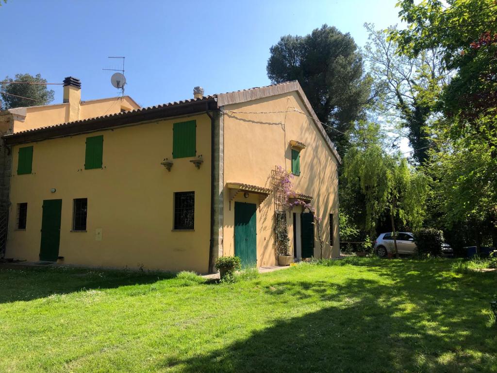 una casa con persianas verdes en un patio verde en Casale del monte, Pesaro, en Pesaro