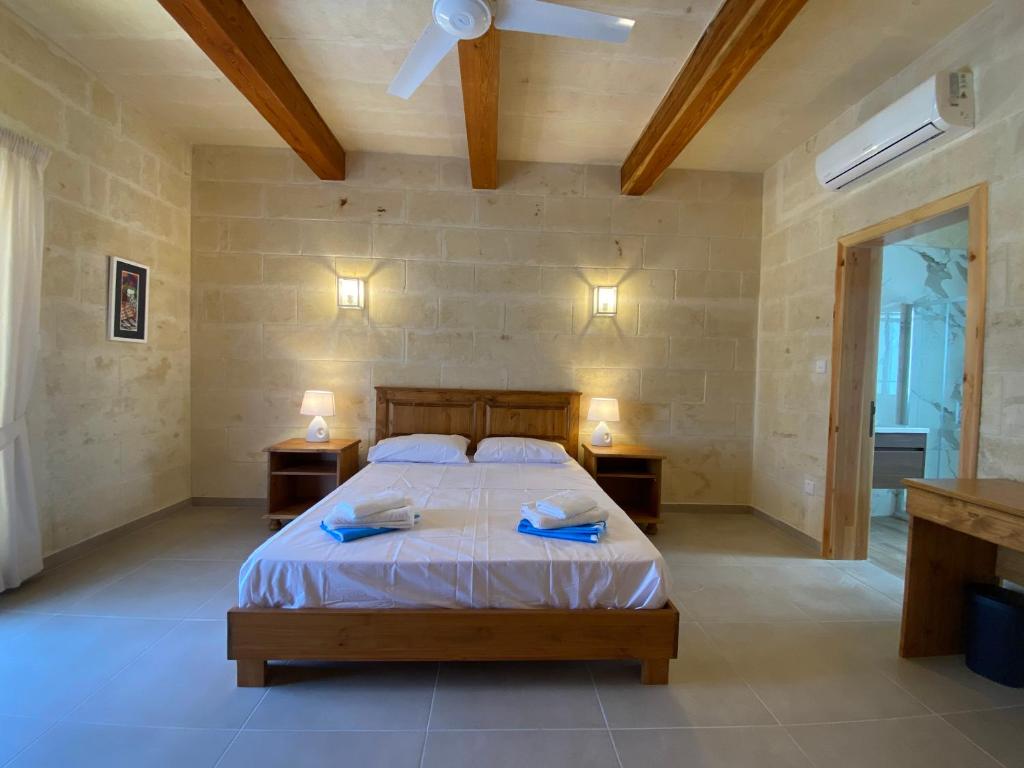 a bedroom with a bed with two night stands and a ceiling fan at Ta' Ganna Farmhouse in Sannat