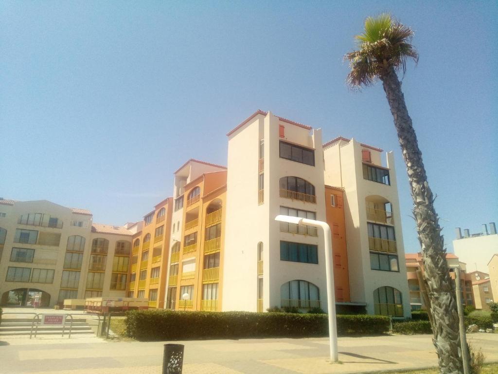 un edificio alto con una palma di fronte di T3 avec magnifique vue mer a Le Barcarès
