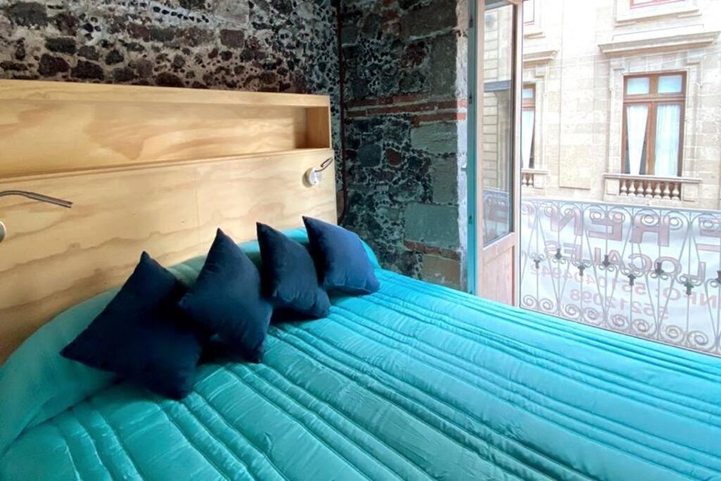 een blauw bed met blauwe kussens in een kamer bij 109 SUITES DONCELES C/BALCON CENTRO HISTÓRICO CDMX in Mexico-Stad