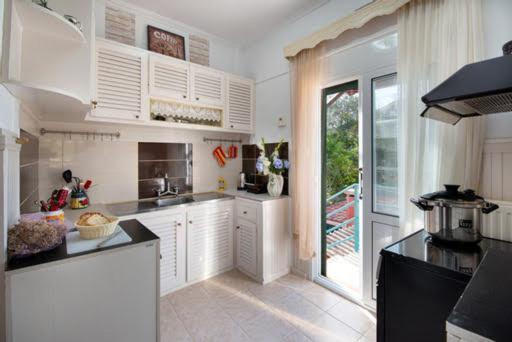 a kitchen with white cabinets and a large window at Alexandra Apartment in Gaios