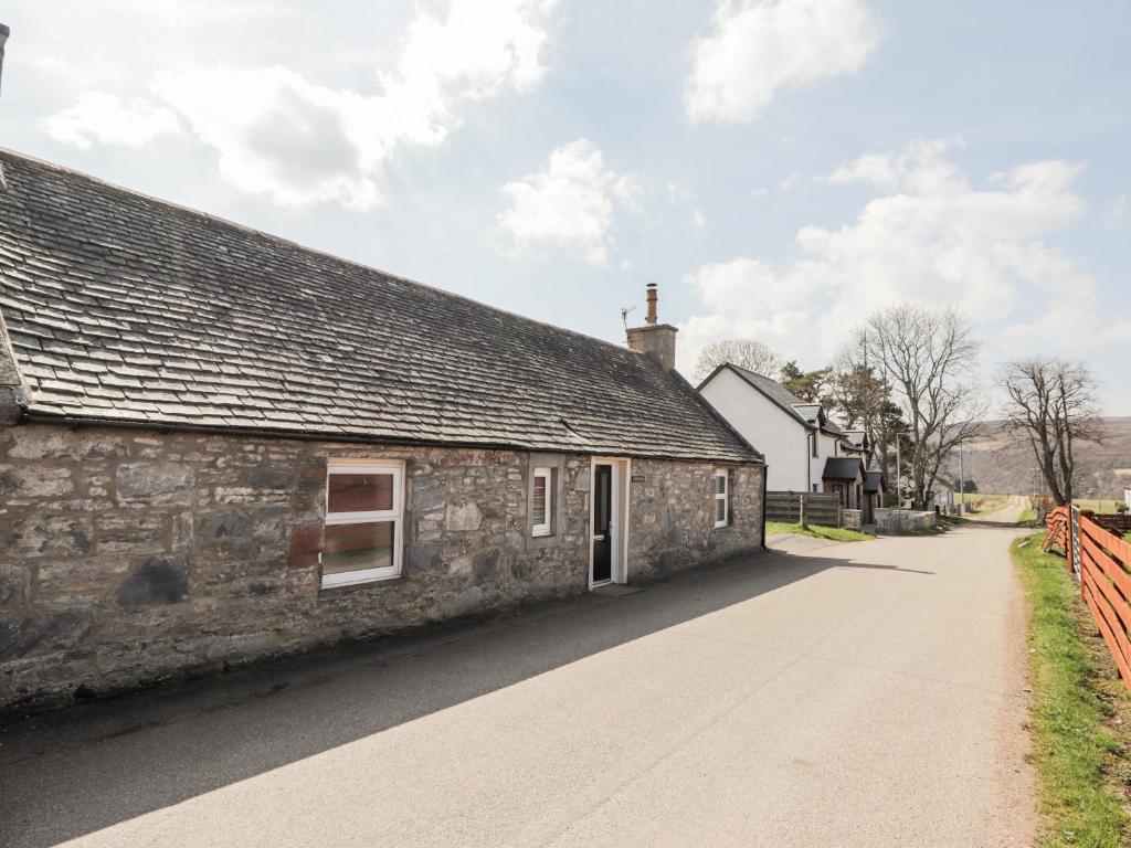 an old stone building with a sidewalk next to it at Livet Cottage in Tomintoul