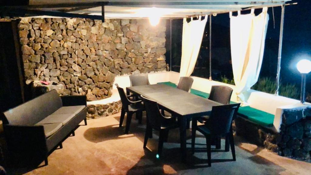 jadalnia ze stołem i krzesłami oraz kamienną ścianą w obiekcie Casa Vacanze Oasi di Venere w mieście Pantelleria