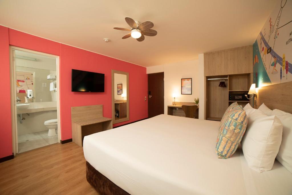 ein Schlafzimmer mit einem weißen Bett und einer roten Wand in der Unterkunft Centro by Casa Andina in Lima