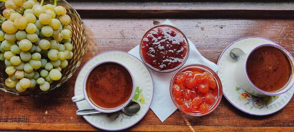 un tavolo con tre ciotole di zuppa e un cesto di uva di Tomor Shehu Guest House a Berat