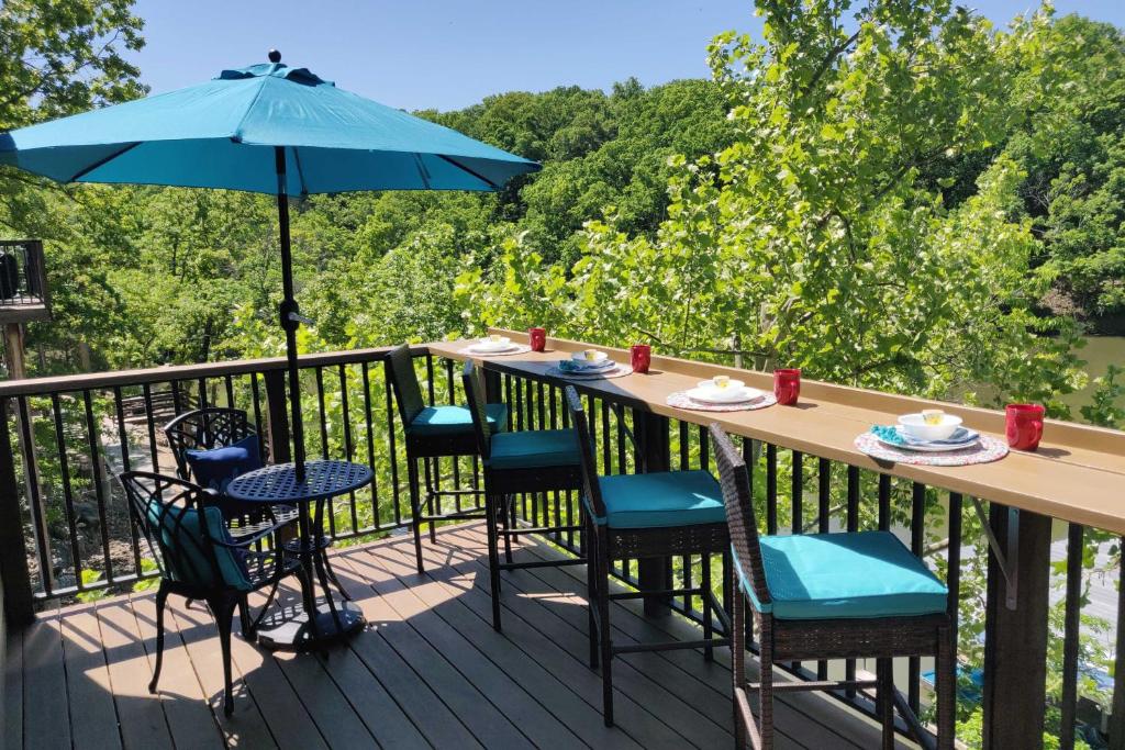 einen Tisch und Stühle auf einer Terrasse mit einem Sonnenschirm in der Unterkunft Lakefront Home in the woods with Community Pool! in Osage Beach