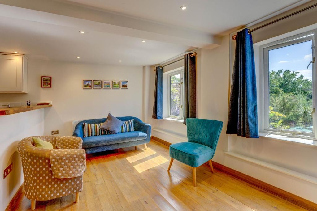 a living room with a blue couch and a chair at Ottery St Mary Cottages in Ottery Saint Mary